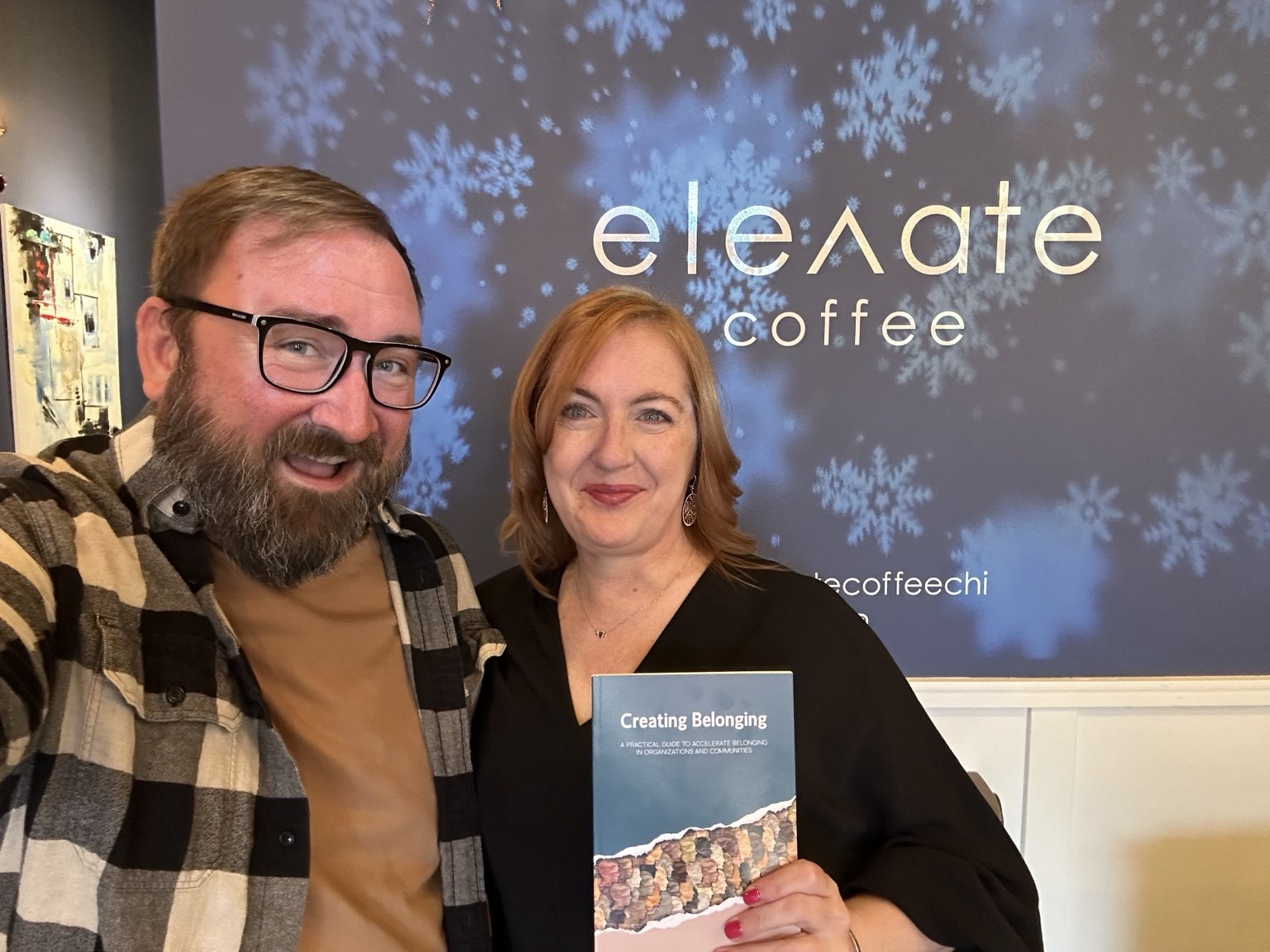 Justin Reinert beside a person holding a copy of Creating Belonging