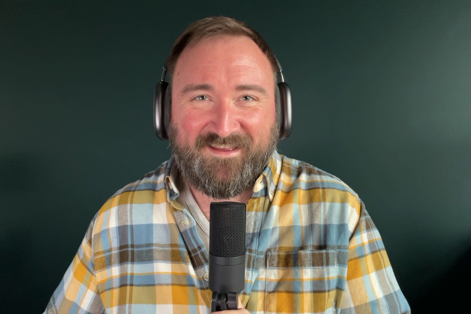 Justin Reinert speaking into a microphone in an earlier portrait